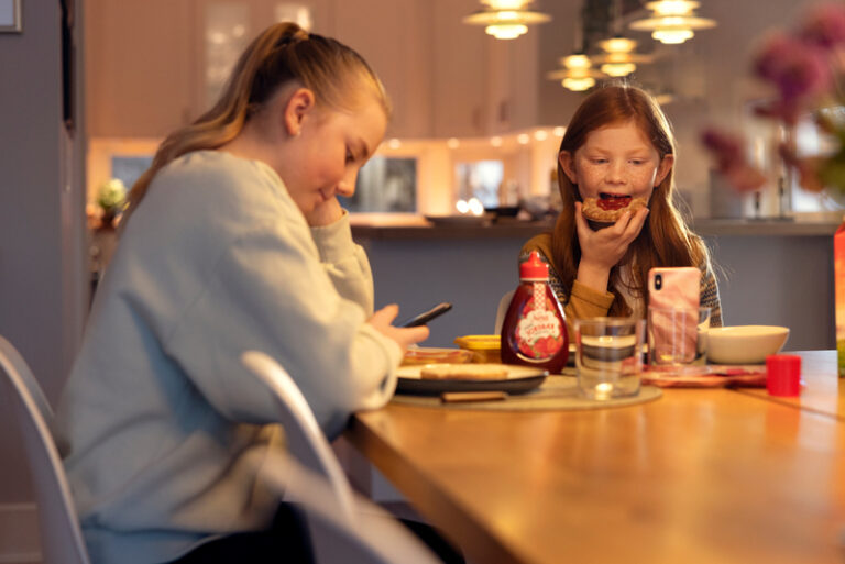 Altibox jenter spiser mat og ser på mobil
